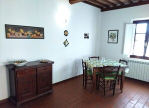 Uma sala de jantar com uma mesa posta para quatro pessoas, um armário de madeira e uma janela com vista.