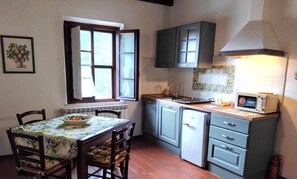 Cozinha compacta com mesa, cadeiras, micro-ondas e armários.