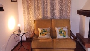 Una habitació amb un sofà, una taula petita amb una làmpada i una cortina amb disseny.