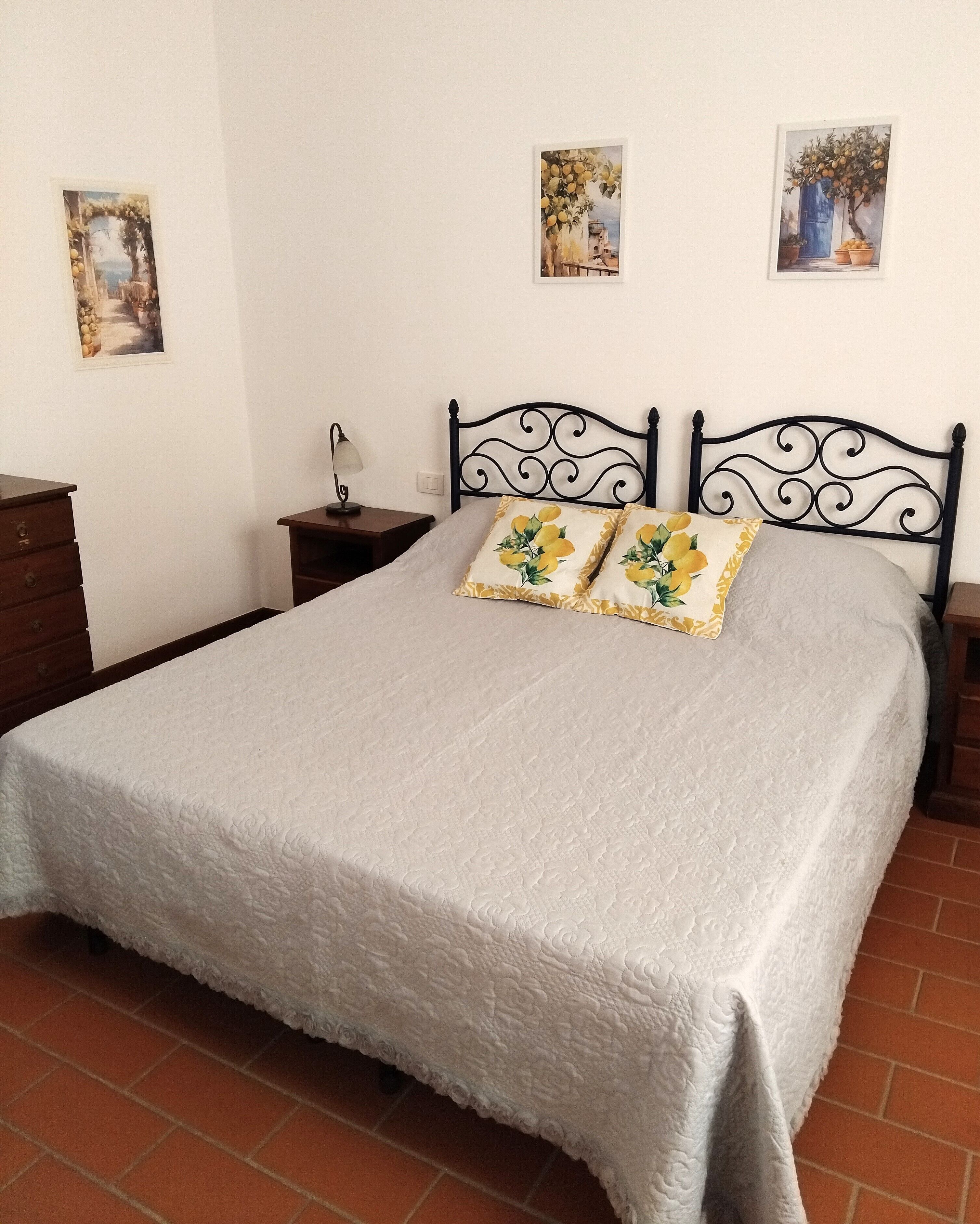 A bedroom with a bed, two nightstands, a dresser, and three wall-mounted paintings.