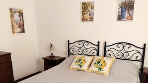 Un dormitori amb un llit, dues tauletes de nit, un armari i tres quadres penjats a la paret.