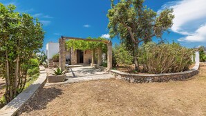 A courtyard with a stone archway, a pathway, and a variety of plants. - 3503 PJE - Casa La Pergola by Barbarhouse (Castrignano del Capo)