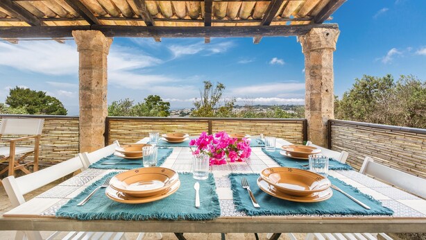 An outdoor dining area with a table set for four, under a wooden pergola with a clear view of the landscape. - 3503 PJE - Casa La Pergola by Barbarhouse (Castrignano del Capo)