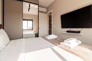 A hotel room with a bed, a TV mounted on the wall, and a bathroom visible through an open door. - B.Homy - VA Perdizes (São Paulo)