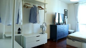 Een slaapkamer met een bed, een dressoir, een spiegel en een kledingkast.