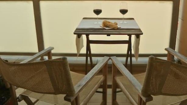 Een eethoek met een tafel en twee rieten stoelen.