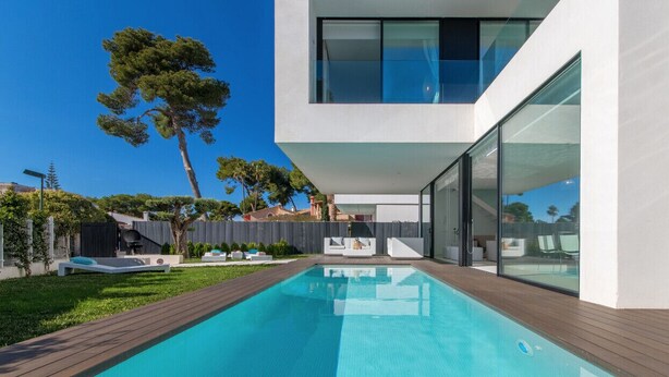Et moderne hus med swimmingpool, terrasse og udsigt over det omkringliggende område.