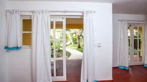 A room with a sliding glass door leading to a garden. - BEACH VIEW PREMIUM 1BR SUITE Ground Floor - Los Corales Beach Village #25 (Punta Cana)