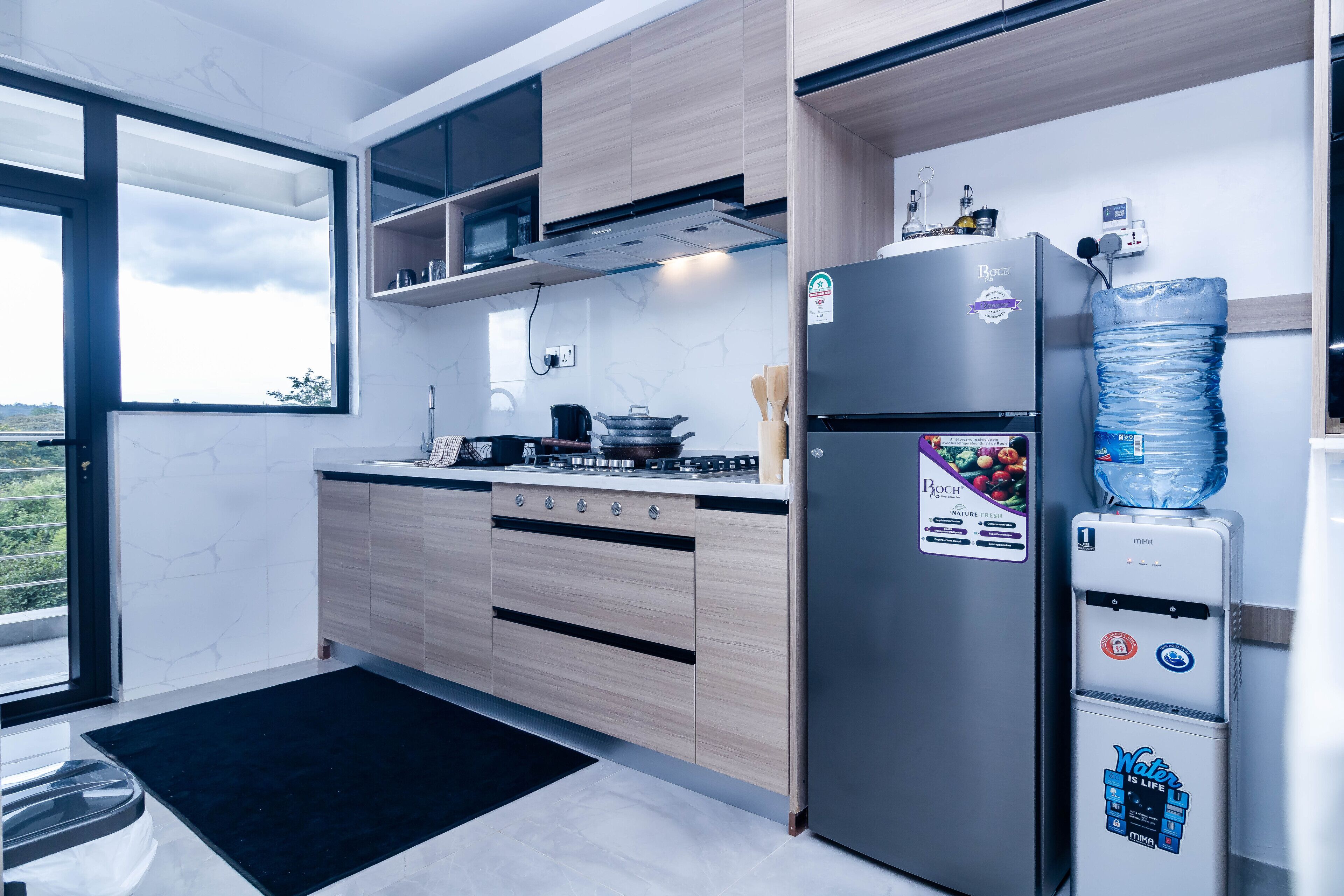 A modern kitchen with a Bosch refrigerator, a water dispenser, and a view through the window.