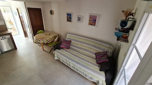 A cozy living room with a sofa, a dining table, and a kitchen area.