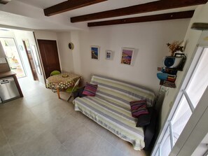 A cozy living room with a sofa, a dining table, and a kitchen area. - Maisonnette du Clos - Avec piscine partagée (Argeles-sur-Mer)