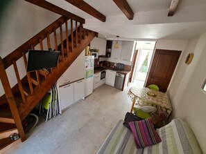 Una cucina con travi in legno, una zona pranzo con tavolo e sedie, e una scala.