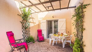 A patio with a table and chairs, a red chair, and a white door.