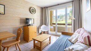 Una habitación acogedora con una pared de madera, televisor, mesa de madera, sofá y vistas al exterior.