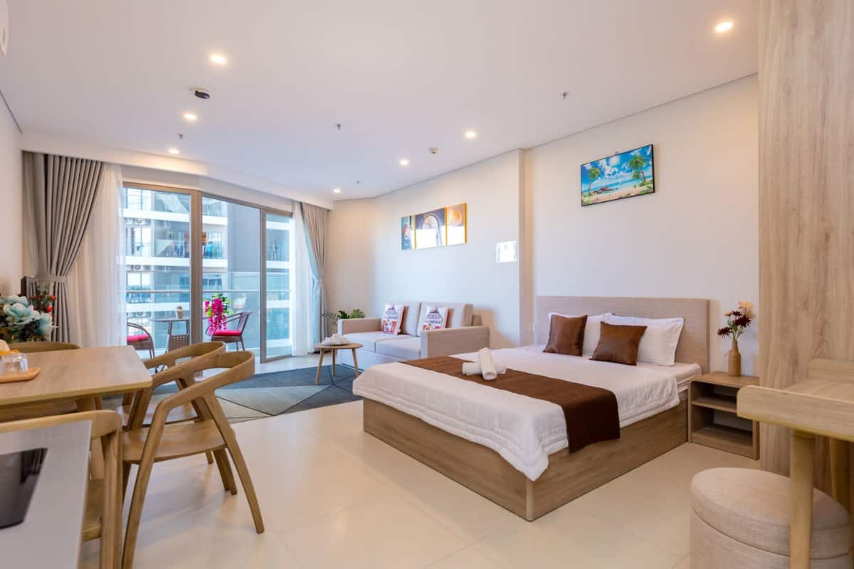 Une chambre d’hôtel moderne dotée d’un grand lit, d’un coin repas et d’un balcon offrant une vue sur la ville.