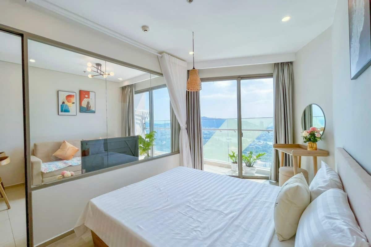 Une chambre d’hôtel moderne dotée d’un grand lit, d’une télévision, d’un balcon avec vue et d’un miroir au mur.