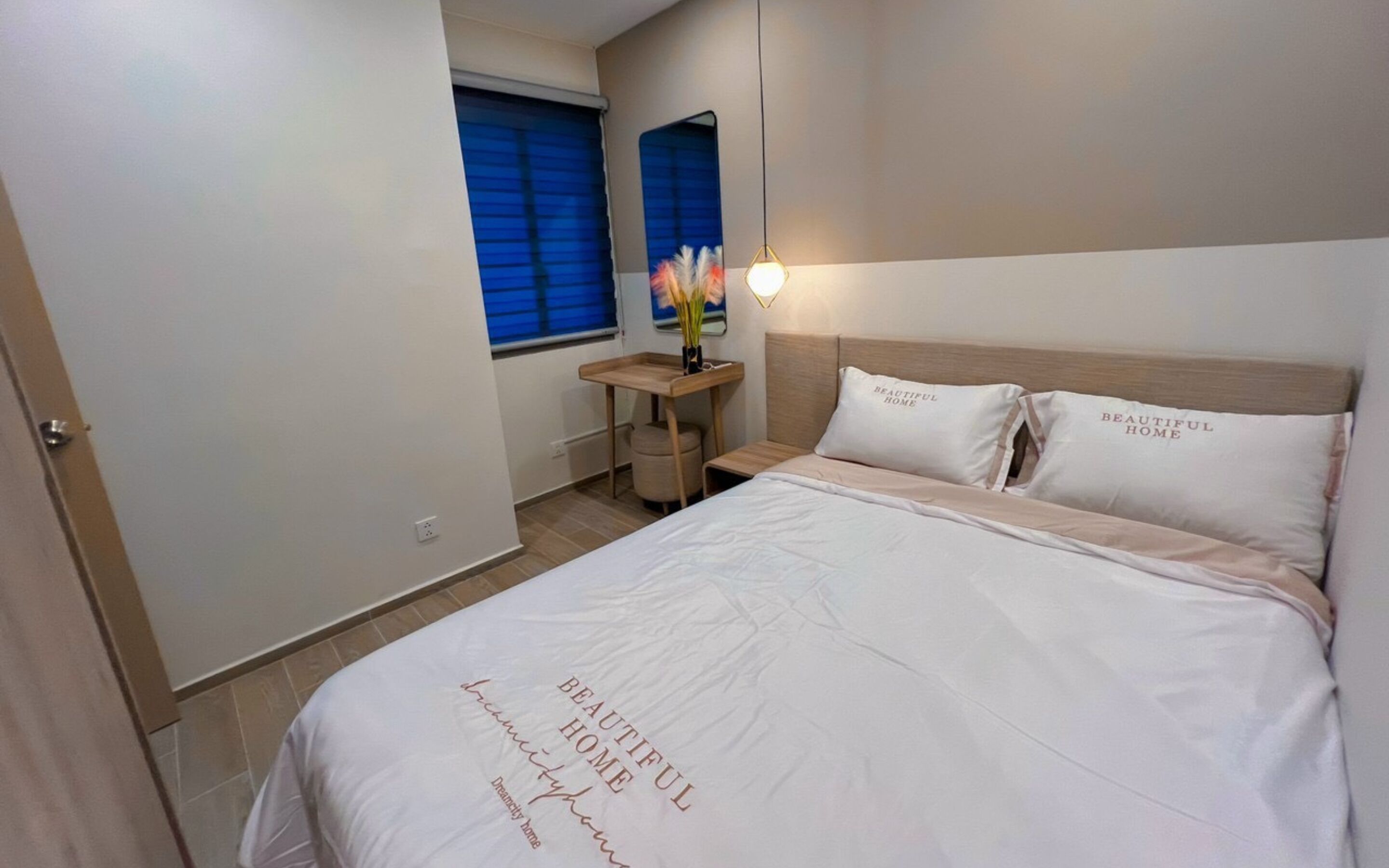 A neatly arranged bedroom with a bed, bedside tables, a small table with a vase, and a window with blinds.