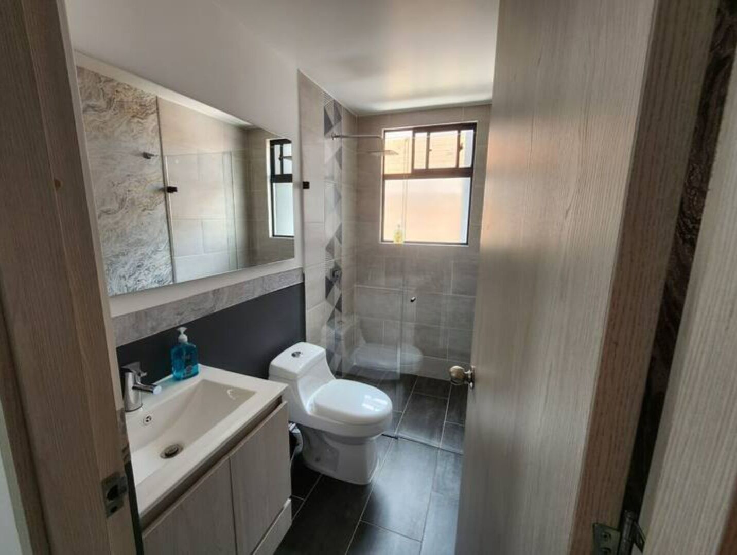 A modern bathroom with a sink, toilet, and shower.