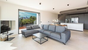 Una sala de estar moderna con un sofá seccional gris, una mesa de centro de vidrio y un televisor de pantalla plana.