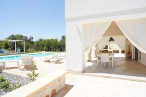 A poolside area with lounge chairs and a covered seating area. - trullo lantane by Pugliadamre (San Michele Salentino)