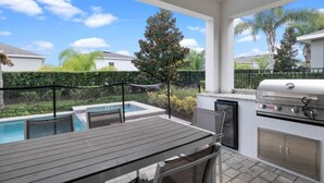 Un patio al aire libre con una parrilla, una piscina y una mesa.