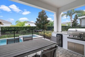 Una terrazza esterna con barbecue, piscina e tavolo.