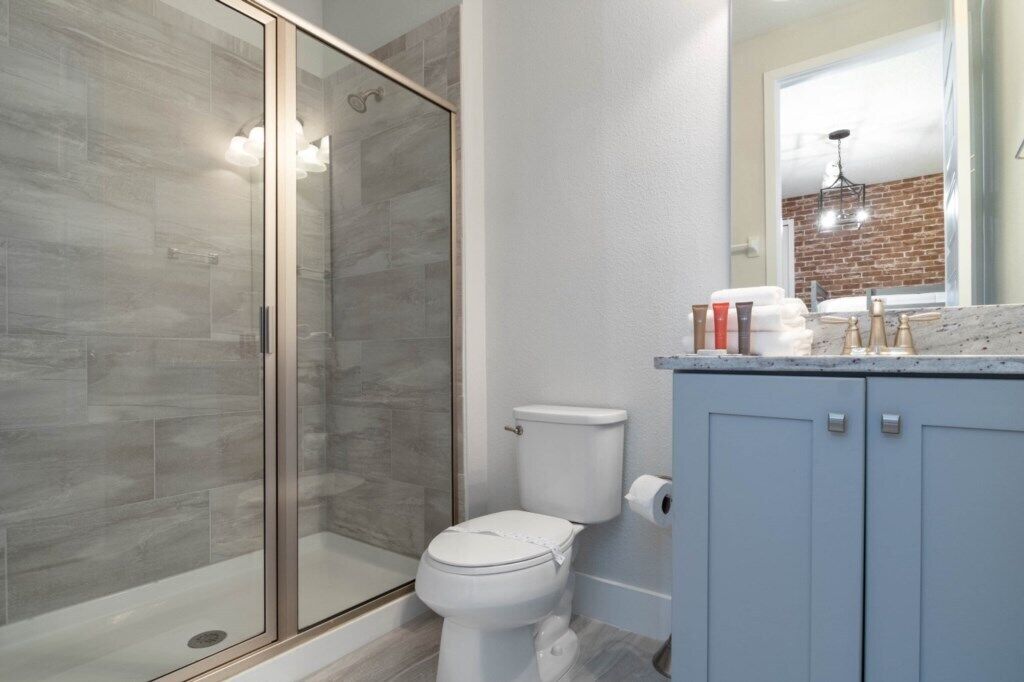 A bathroom with a glass shower enclosure, a toilet, and a vanity with cabinets.