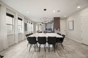 A modern kitchen with grey cabinets, a central island, and a dining area with a large table and chairs.