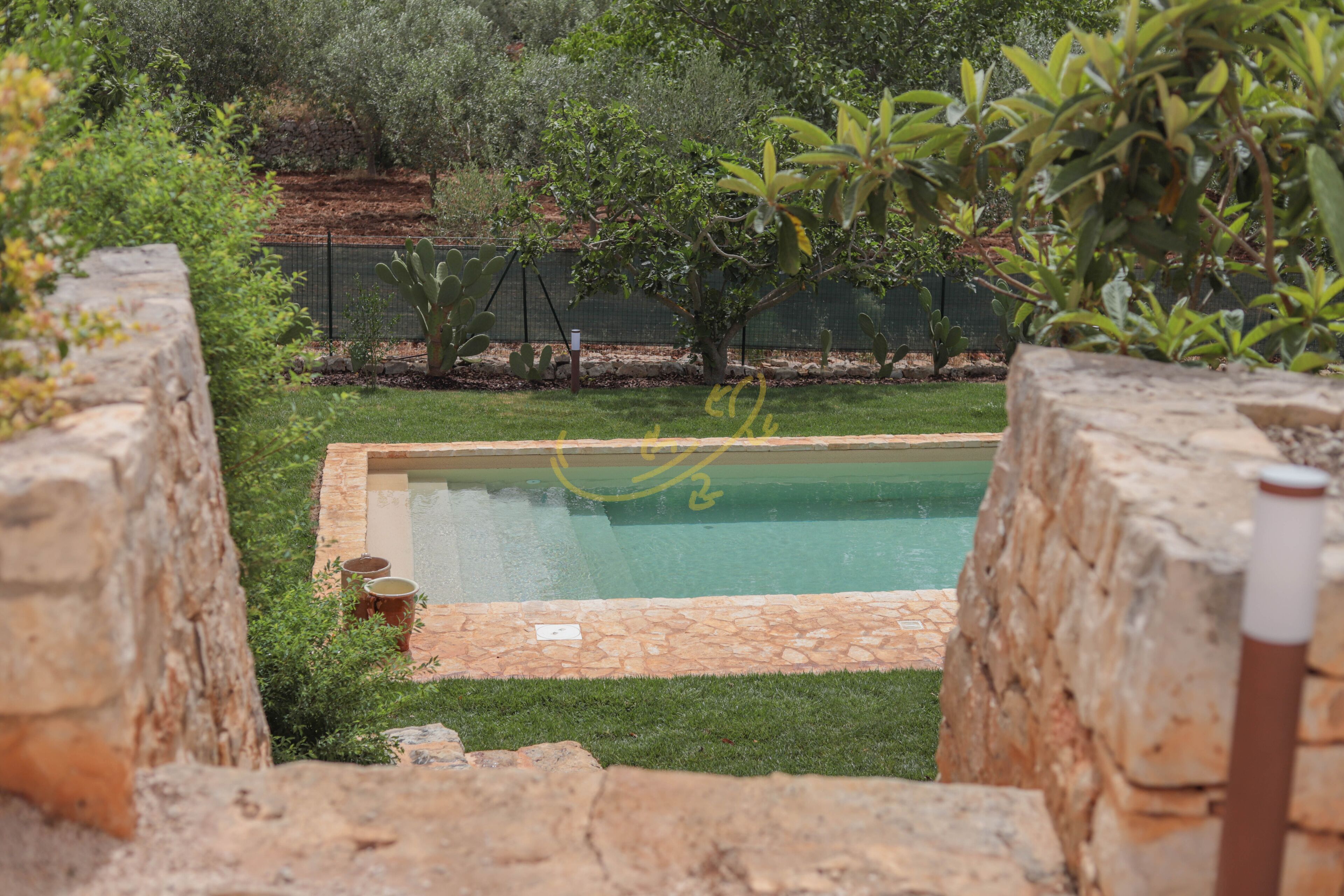 A swimming pool surrounded by stone walls and greenery.