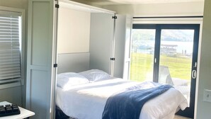 Une chambre à coucher avec un lit, un ventilateur de plafond, une fenêtre et une porte.