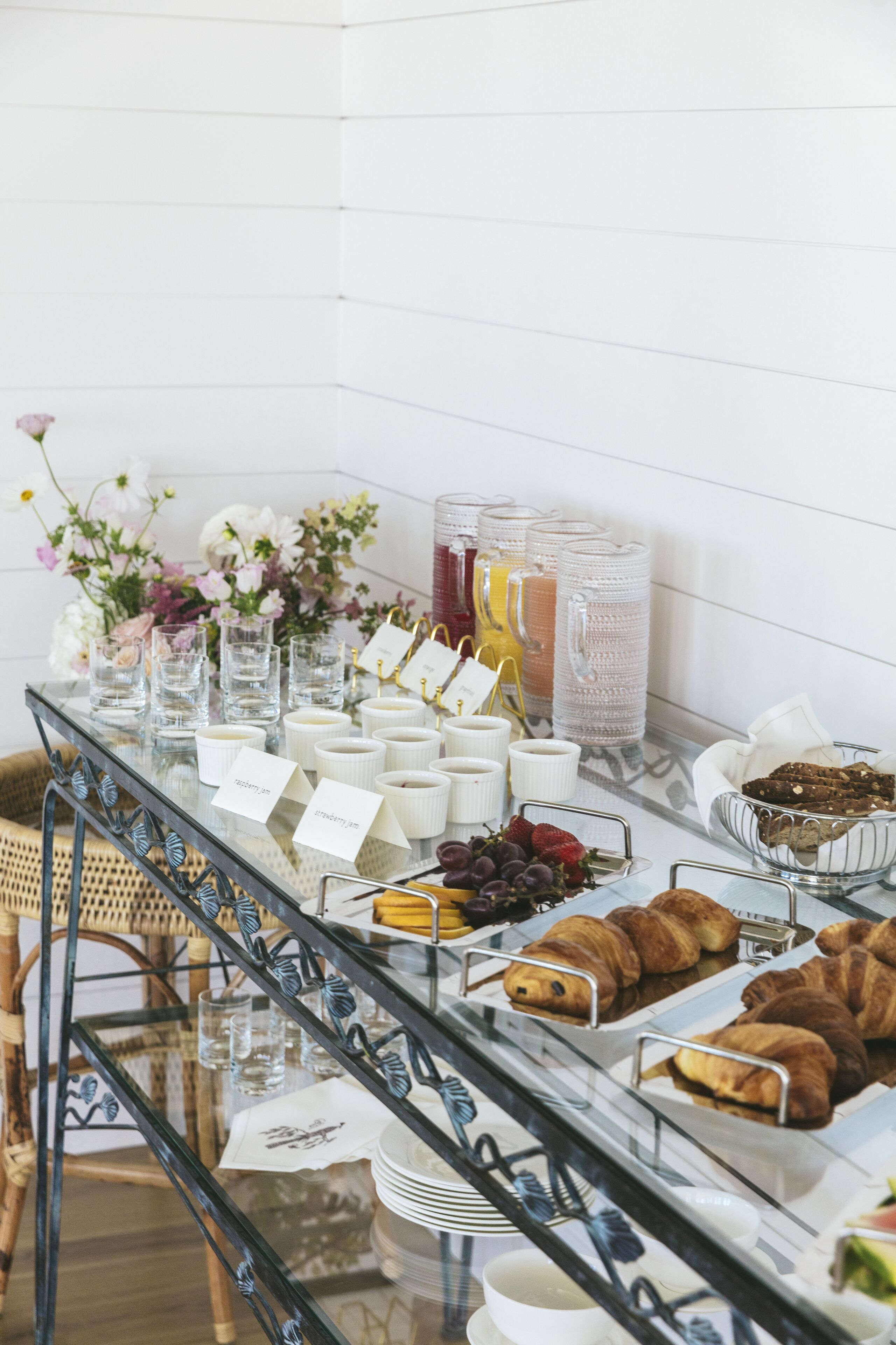 A buffet table with various food items, including fruits, pastries, and beverages.