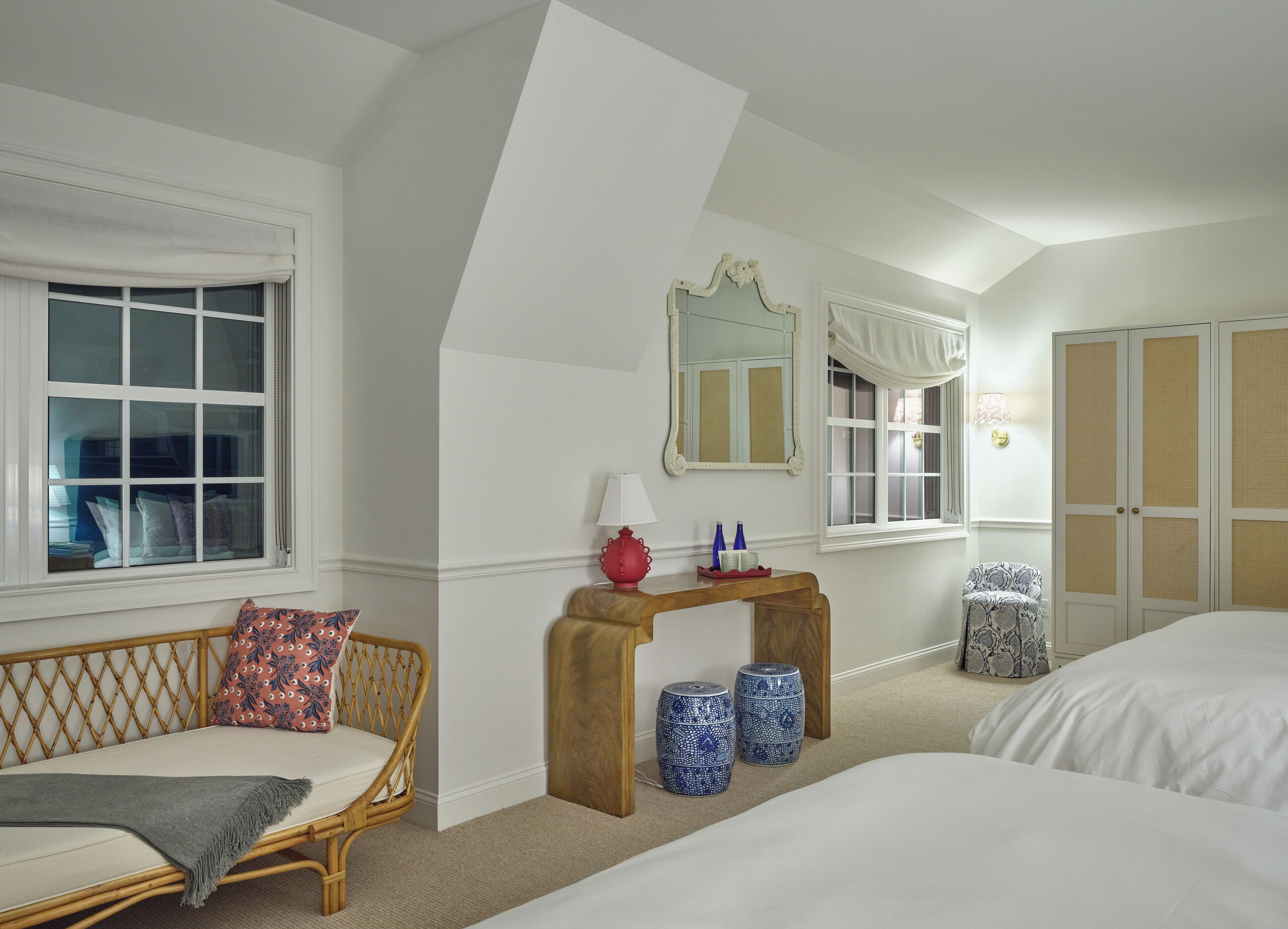 A hotel room with a bed, a sofa, a console table with decorative items, a mirror, and a wardrobe.