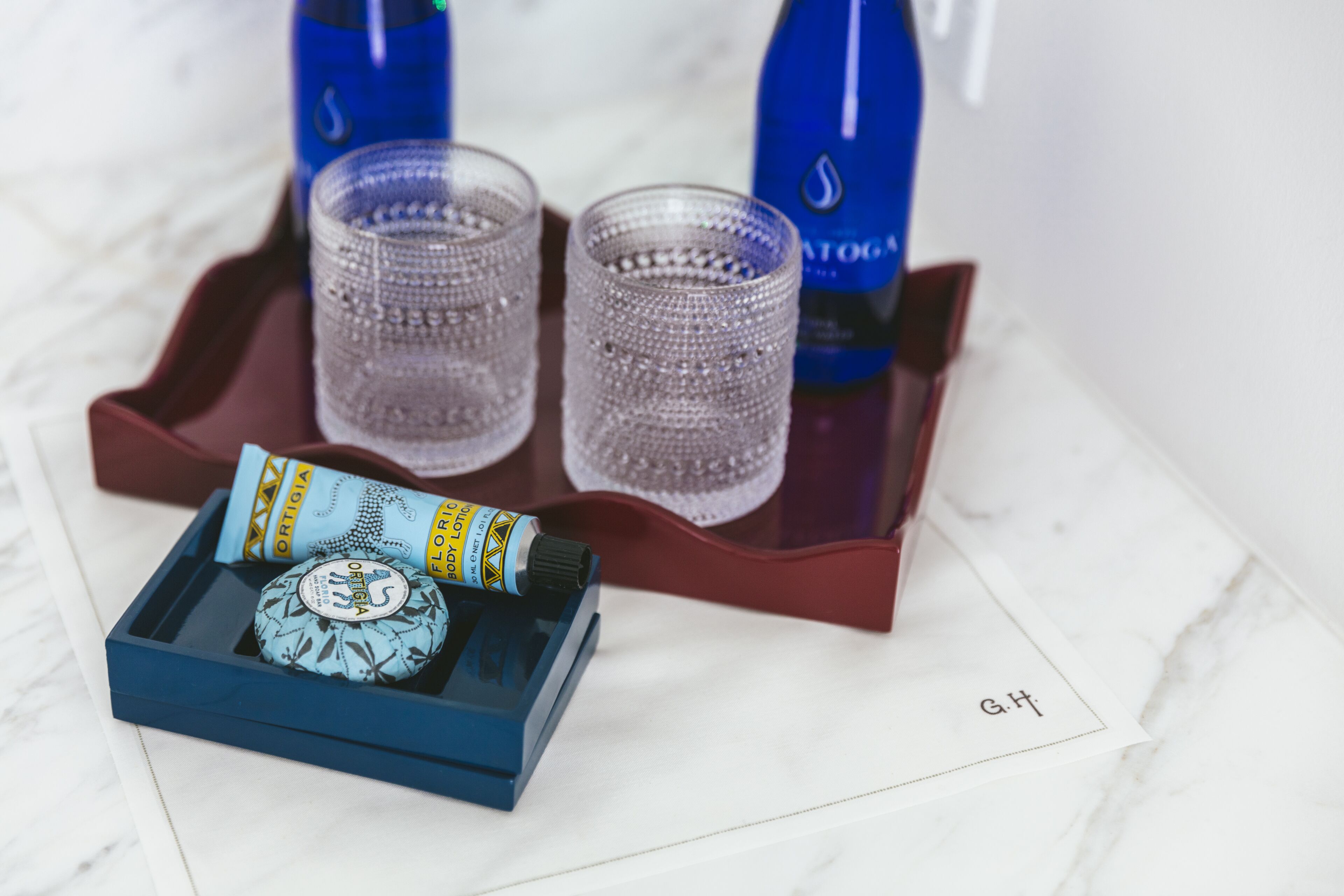 A tray with two glasses of water, a bottle of water, and a box of chocolates.