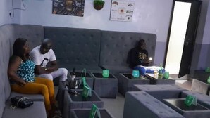 Un área de estar con sofás y sillones, una mesa con objetos, y una puerta al fondo.