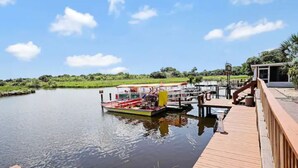 A riverfront dock with a boat and a building with a red roof.