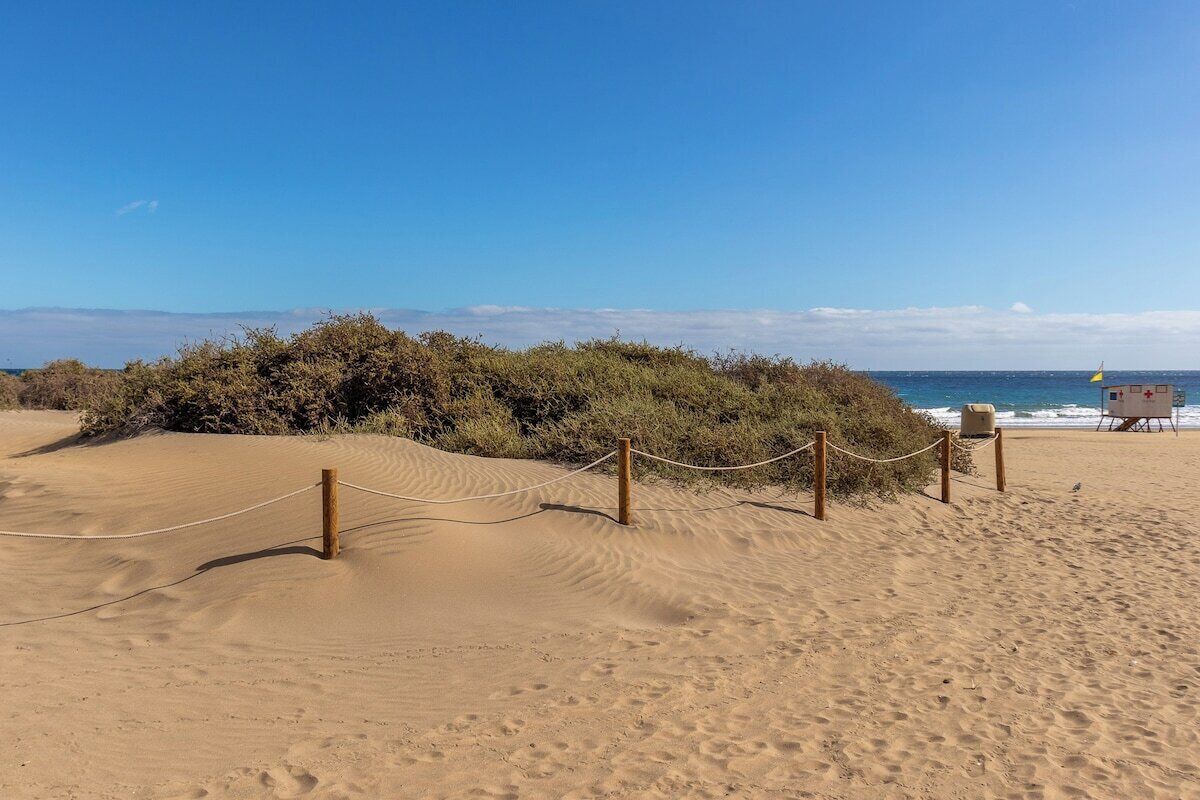 A sandy beach with a lifeguard station and a rope barrier.