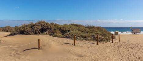 A sandy beach with a lifeguard station and a rope barrier.