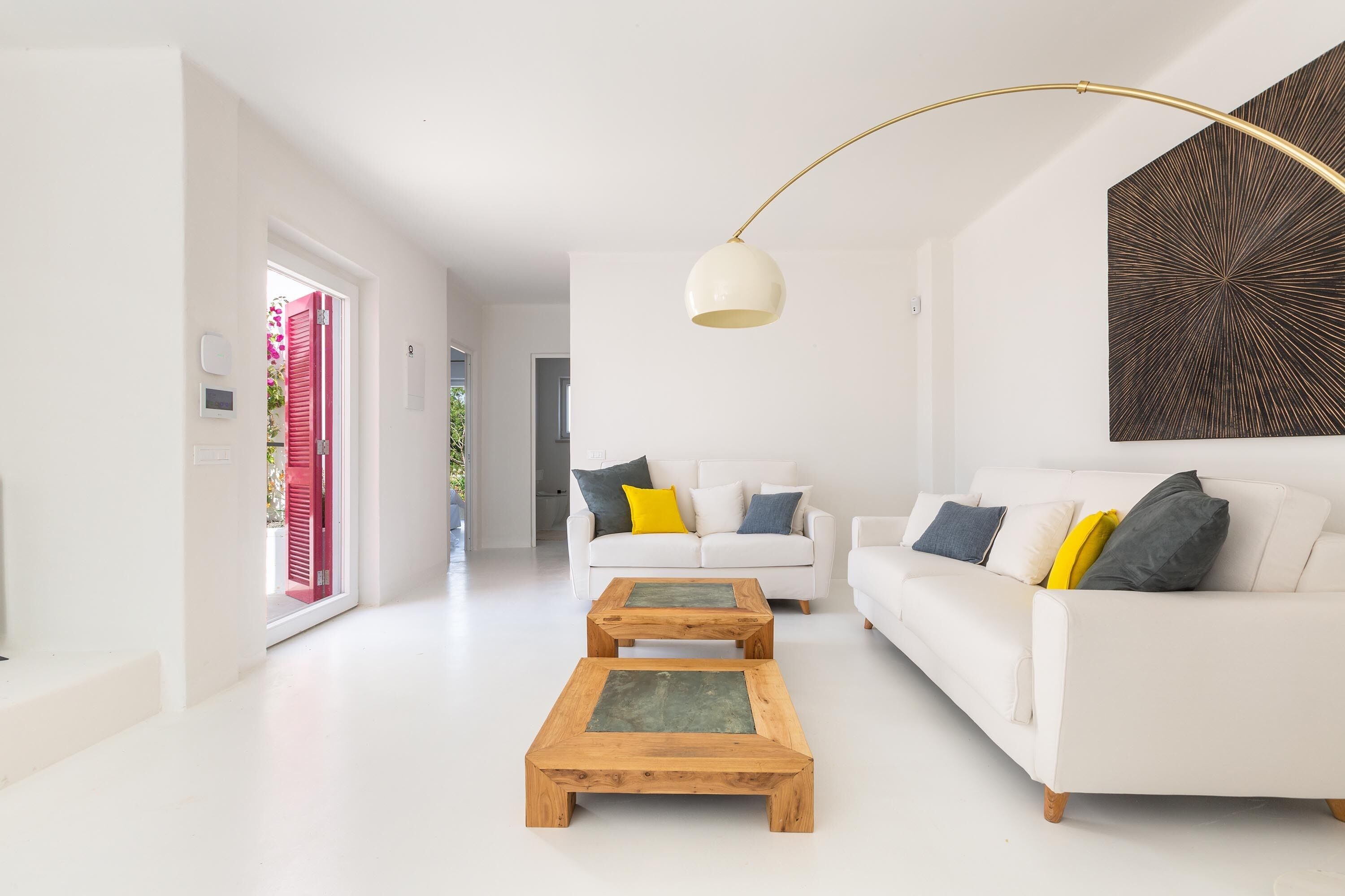 A modern living room with a white sofa, two wooden coffee tables, and a floor lamp.
