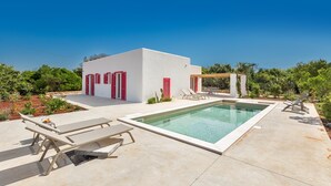 Eine moderne Villa mit Swimmingpool, Außenmöbeln und einer Pergola.