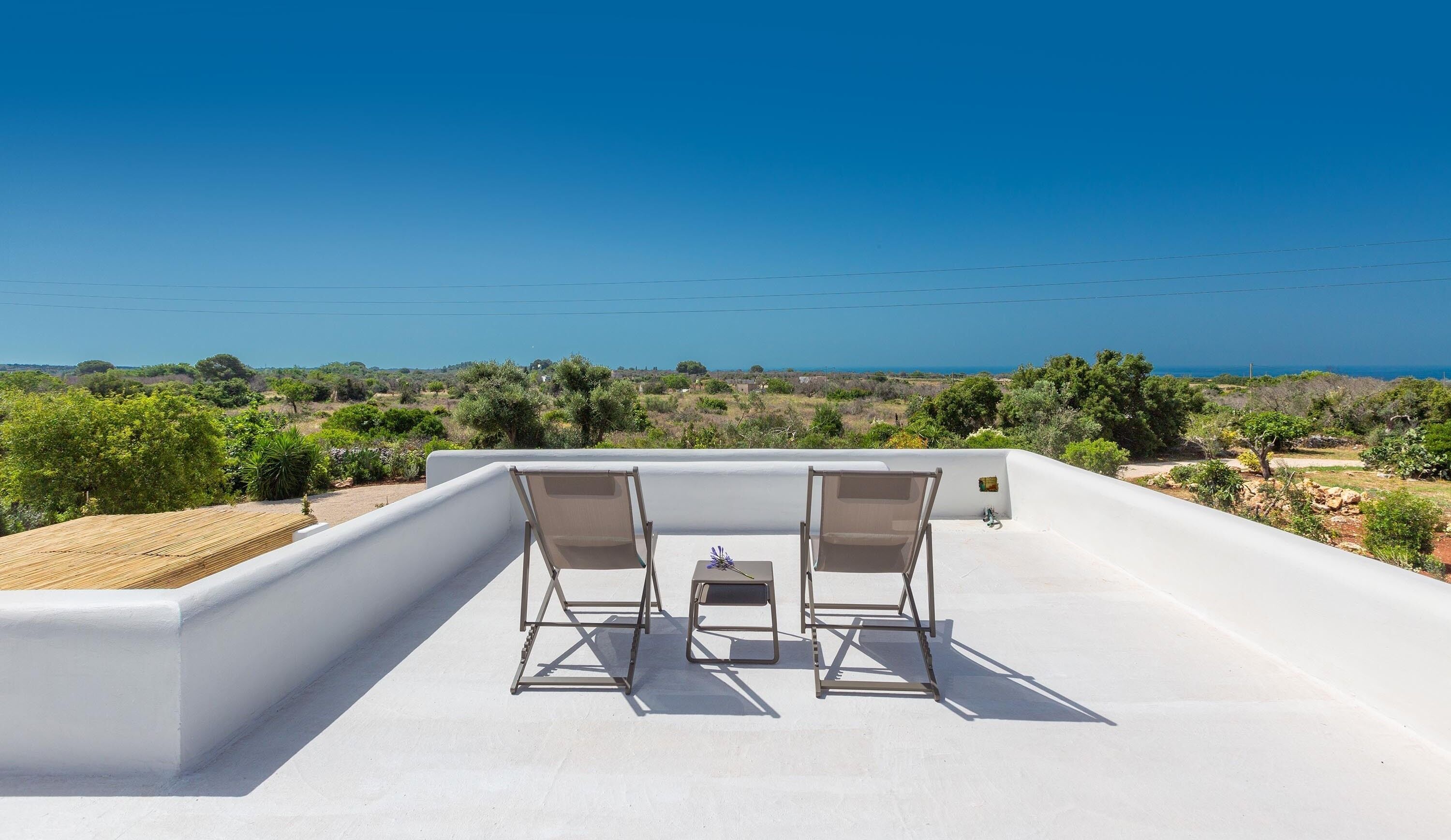 Une terrasse sur le toit, avec deux chaises et une petite table, d’où l’on peut admirer un paysage côtier.