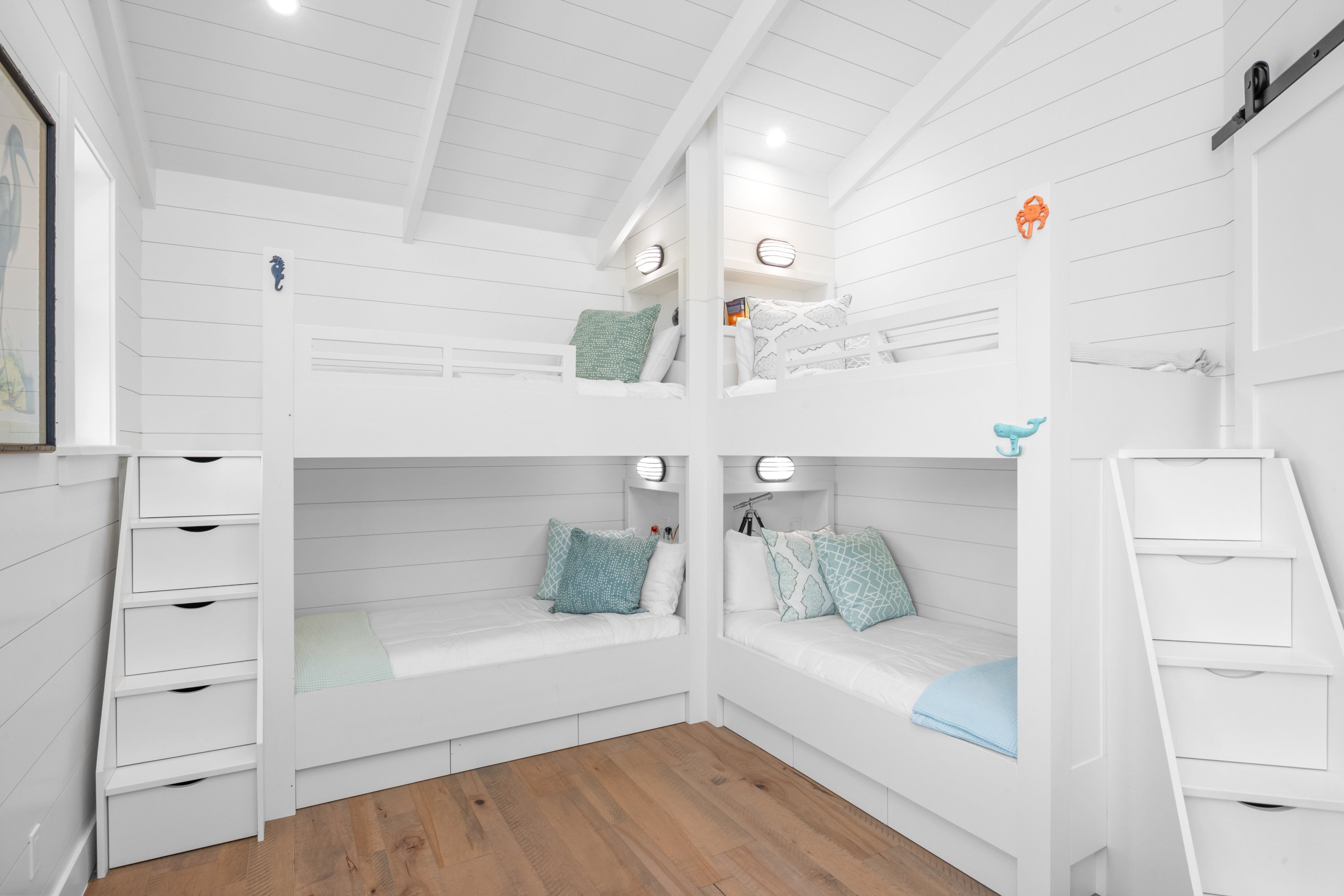 A bunk bed room with white walls and wooden flooring.