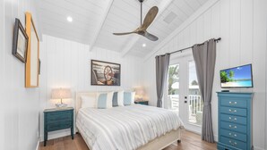 A bedroom with a bed, a ceiling fan, a TV, a dresser, and a door leading to a balcony. - Located in Captiva Village! Beautifully Designed Pool Home (Captiva)