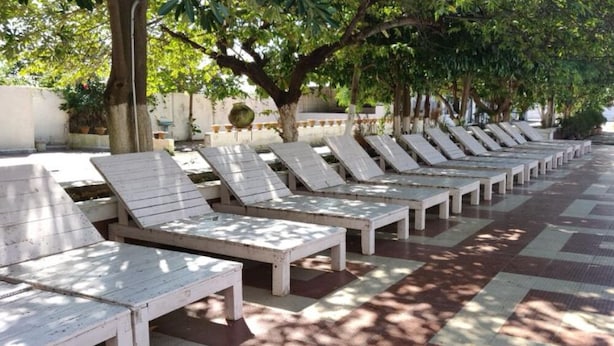 Een rij witte lounge stoelen met metalen frames, gerangschikt in een lijn langs een betegelde looppad.