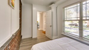 A bedroom with a large window, a brick wall, and a door leading to another room. - Chic Newark Vacation Rental: 3 Mi to Airport! (Newark)