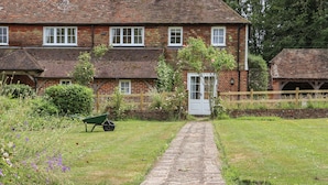 A traditional brick house with a paved pathway leading to a white door. - Mountfield Farm Cottage (Ashford)