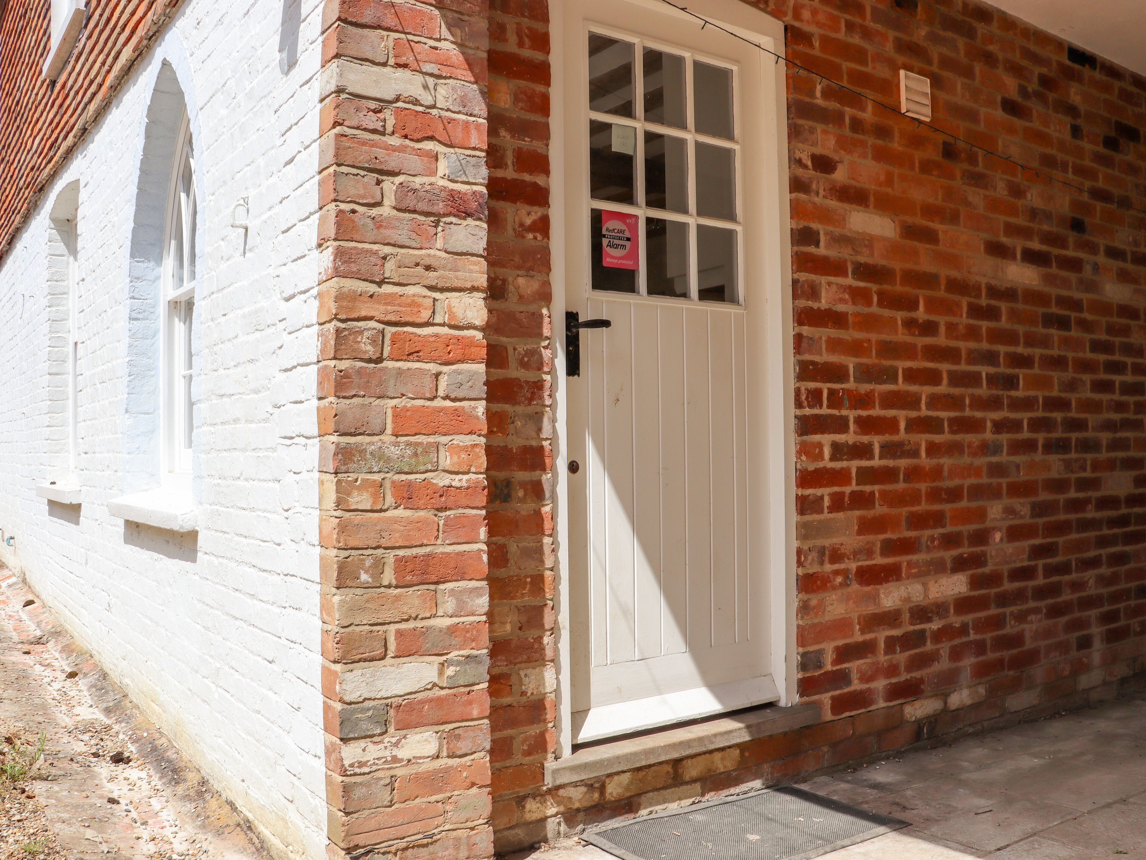 A white door with a window, a brick wall, and a small window on the left.