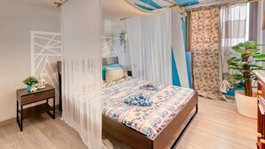 Un dormitorio con cama, mesita de noche, planta en maceta y ventana con cortinas.