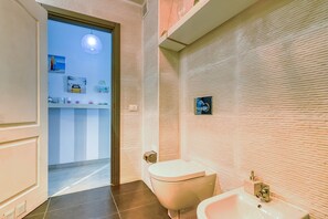 A bathroom with a toilet, sink, and a mirror on the wall.
