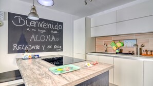 Una cocina moderna con una isla central, una pizarra con un mensaje de bienvenida y un diseño minimalista.