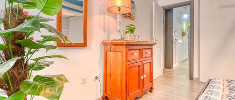 A room with a wooden cabinet, a mirror, and a potted plant.